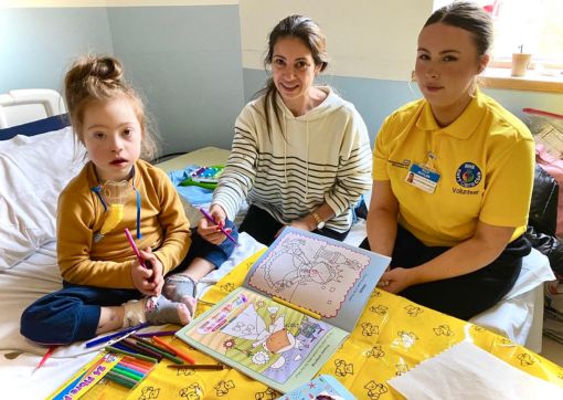 Volunteer Ella colouring in with one of our patients and their mum