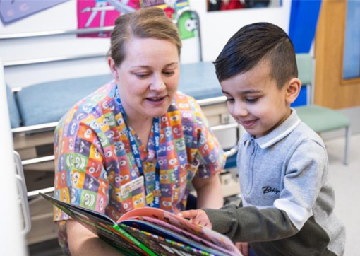 Play therapist, Chantelle Tiplady, with a young patient looking at a book